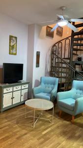 a living room with two blue chairs and a tv at Apartamentos Arcos Duplex Águilas in Águilas