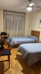 a bedroom with two beds and a window with a fan at Apartamentos Arcos Duplex Águilas in Águilas