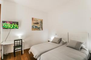 twee bedden in een kamer met een tv aan de muur bij Guia Getaway Private Rooms in Santa Maria de Guia de Gran Canaria