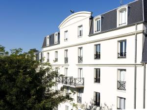 un bâtiment blanc avec un toit noir dans l'établissement ibis Valenciennes, à Valenciennes