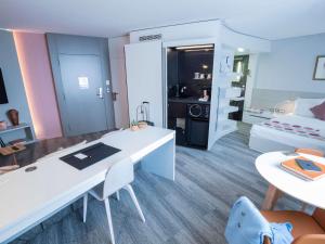 een grote woonkamer met een witte tafel en een bed bij Novotel Suites Luxembourg in Luxemburg