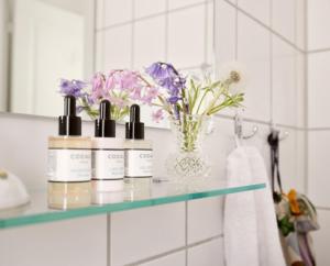 a bathroom with three bottles ofodorizers on a counter with flowers at Villa Strand in Hornbæk