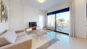 uma sala de estar com um sofá e uma televisão em Elegant apartment with pool AC and balcony em Arenales del Sol