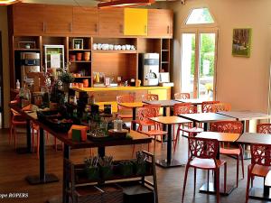 a restaurant with tables and chairs and a kitchen at ibis Styles Gien in Gien
