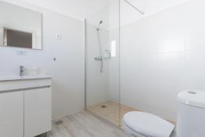 La salle de bains blanche est pourvue de toilettes et d'une douche en verre. dans l'établissement Galagana Charm House, à Golegã