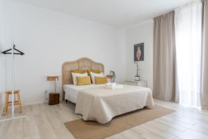 um quarto branco com uma cama com almofadas amarelas em Galagana Charm House na Golegã