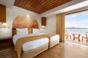 A bed or beds in a room at Ramada Loutraki Poseidon Resort