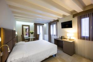 a bedroom with a bed and a desk and a television at Leone Hotel in Venice