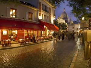 a group of people walking down a street at night at Mercure Paris Pigalle Sacre Coeur in Paris