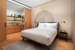 a bedroom with a large white bed and a kitchen at BEI Zhaolong Hotel, JdV by Hyatt in Beijing