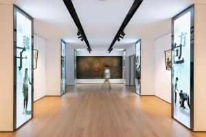 a woman walks through an art gallery with paintings at BEI Zhaolong Hotel, part of JdV by Hyatt in Beijing