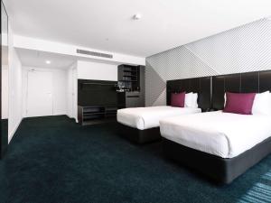 a hotel room with two beds with purple pillows at Movenpick Hotel Melbourne On Spencer in Melbourne