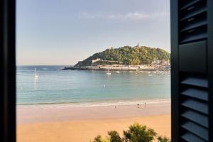a view of a beach with a island in the water at Nobu Hotel San Sebastián in Donostia-San Sebastián