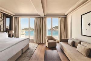 a hotel room with a bed and a couch and windows at Nobu Hotel San Sebastián in Donostia-San Sebastián