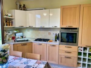 cocina con armarios de madera, mesa y fogones en La casa di Lory, en Sarnano