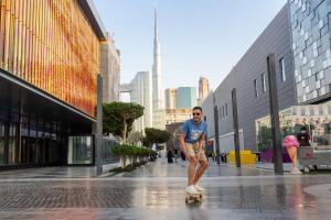 Un uomo che cavalca uno skateboard lungo una strada di città di Rove City Walk a Dubai