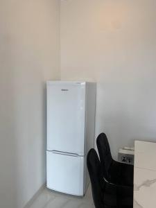 een witte koelkast en een zwarte stoel in een kamer bij Agarak House 