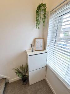 a room with a dresser and a window with a plant at Koselig Properties in Lerwick