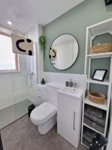 a bathroom with a toilet and a sink and a mirror at Koselig Properties in Lerwick