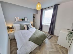 a white bedroom with a bed and a window at Koselig Properties in Lerwick