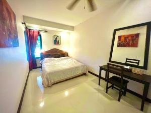 a bedroom with a bed and a table and a mirror at Grand Villa Khaolak in Khao Lak