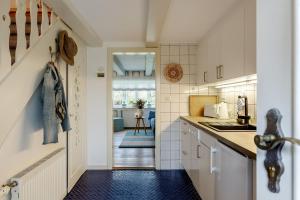 una cucina con armadi bianchi e pavimento piastrellato blu di Im Lütten a Braderup