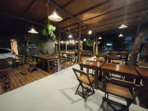 un restaurante con mesas de madera, sillas y luces en Taipu In House, en Maraú