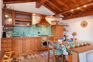 cocina con armarios de madera, mesa y fogones en Baita Margherita, en Casargo