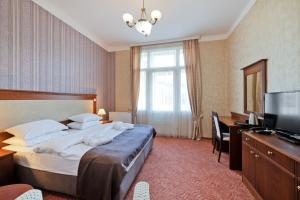 um quarto de hotel com uma cama grande e uma televisão em Hotel Aura em Mariánské Lázně