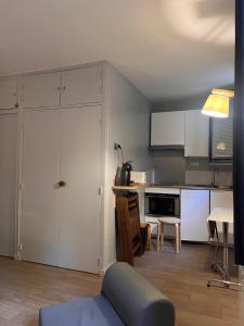 cocina con armarios blancos, mesa y comedor en Studio rénové au pied des pistes, en Font-Romeu