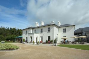 duży biały dom ze stołami i parasolami w obiekcie The Lodge at Ashford Castle w mieście Cong