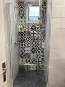 y baño con ducha y azulejos blancos y negros. en Neuilly-sur-Seine calme et lumineux. B&B. 3 chambres en Neuilly-sur-Seine