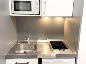 eine kleine Küche mit einer Spüle und einer Mikrowelle in der Unterkunft Apartamentos Midi 3000 in Formigal