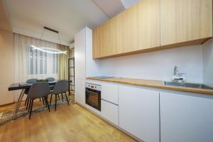 a kitchen with white cabinets and a table with chairs at Apartment Alpi in Peje