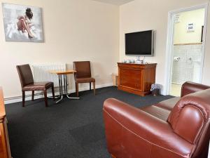 ein Wohnzimmer mit einem Sofa und einem TV in der Unterkunft The Goodlife Guesthouse in Harwich