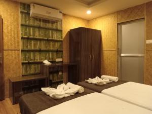 two beds in a room with bookshelves and towels at Sawasstika Eco Park Resort in Binnāguri +41 photos