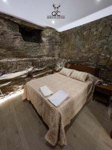 1 dormitorio con cama y pared de piedra en Quinta da Coitada - Alojamento Local, en Soutelo do Douro