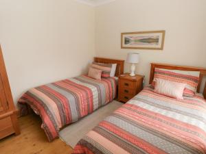 een slaapkamer met 2 bedden en een lamp op een houten vloer bij Highmead in Burry Port