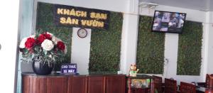 a room with a green wall with a clock and flowers at Sân Vườn Hotel Khánh Hòa in Ninh Hòa