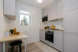 a kitchen with white cabinets and a table in it at SuperApart Walerego Sławka 3 in Warsaw