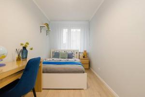 um quarto com uma cama, uma secretária e uma cadeira azul em SuperApart Walerego Sławka 3 em Varsóvia