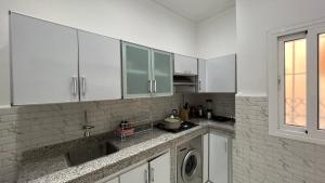 a kitchen with white cabinets and a washing machine at Tangier city center in Tangier