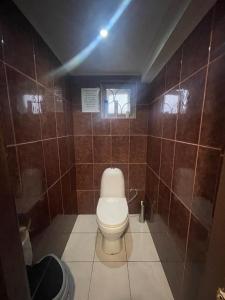 a bathroom with a toilet in a brown tiled wall at Мир in Ochamchira