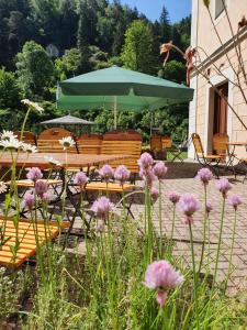 a table and chairs with a green umbrella and flowers at Hotel Garni Dekorahaus in Bad Schandau