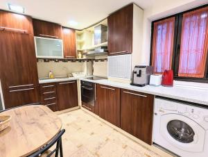 a kitchen with wooden cabinets and a table and a washing machine at Maisonette Balcesco in Braşov