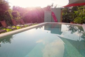 una piscina con sillas y el sol reflejo en el agua en Boutique Tropical Retreat, Sleeps 10, Perfect for Friends and Fams en Sámara