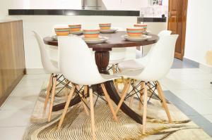 a dining room with a wooden table and white chairs at Roma Stays - Hibiscus Homes Cozy 3 bedroom near Pride Inn in Mombasa