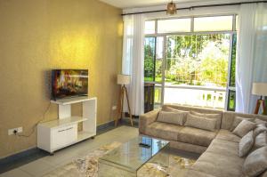 een woonkamer met een bank en een tv bij Roma Stays - Hibiscus Homes Cozy 3 bedroom near Pride Inn in Mombasa