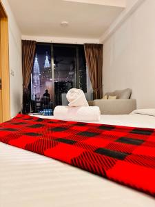 クアラルンプールにあるThe Luxe Colony KLCC BY Infinitumのベッドに赤い毛布が備わるホテルルームです。