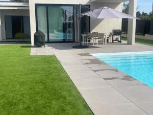 a swimming pool with an umbrella next to a house at Splendide villa proche de Colmar in Bischwihr